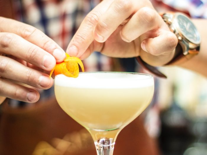 Bartender garnishing cocktail with orange peel in elegant glass