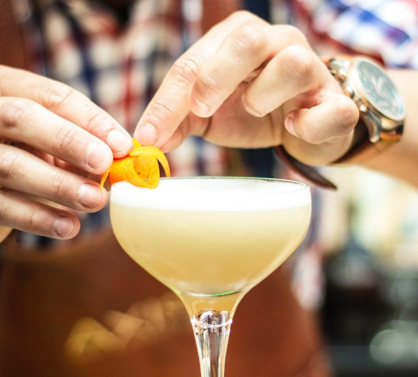Bartender garnishing cocktail with orange peel in elegant glass