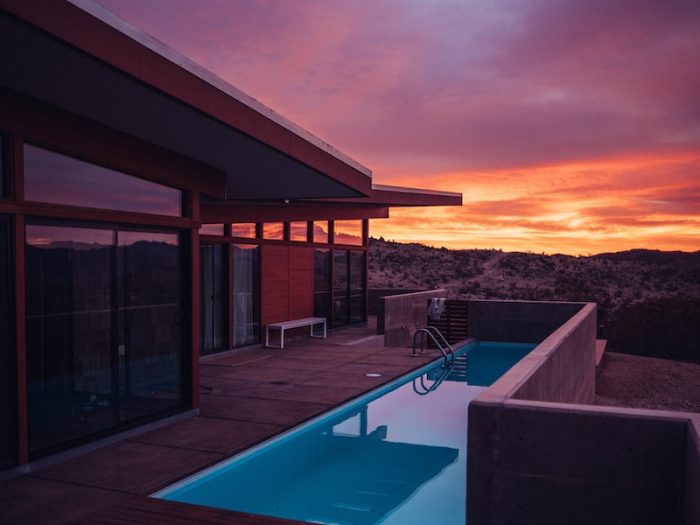 Modern house with pool at sunset, featuring vibrant purple and orange skies in a desert landscape
