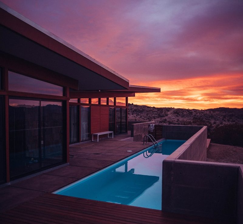 Modern house with pool at sunset, featuring vibrant purple and orange skies in a desert landscape