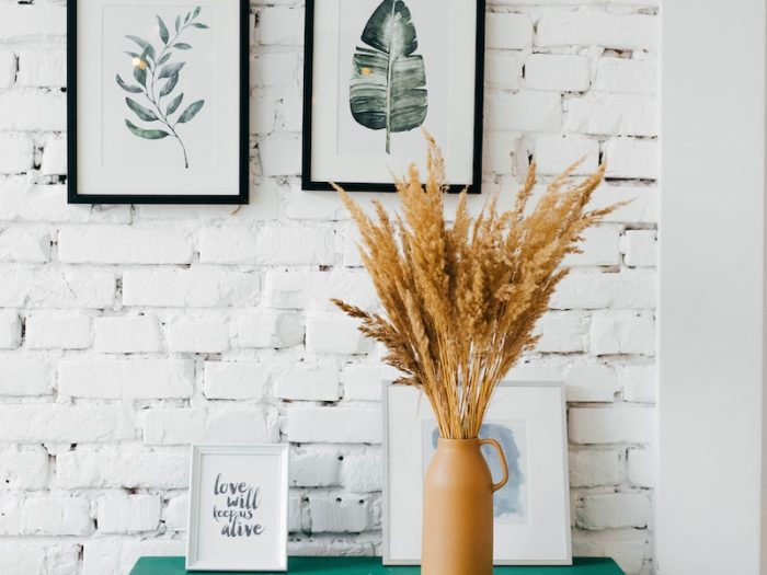 Cosy room with botanical art, green dresser and wheat vase against white brick wall